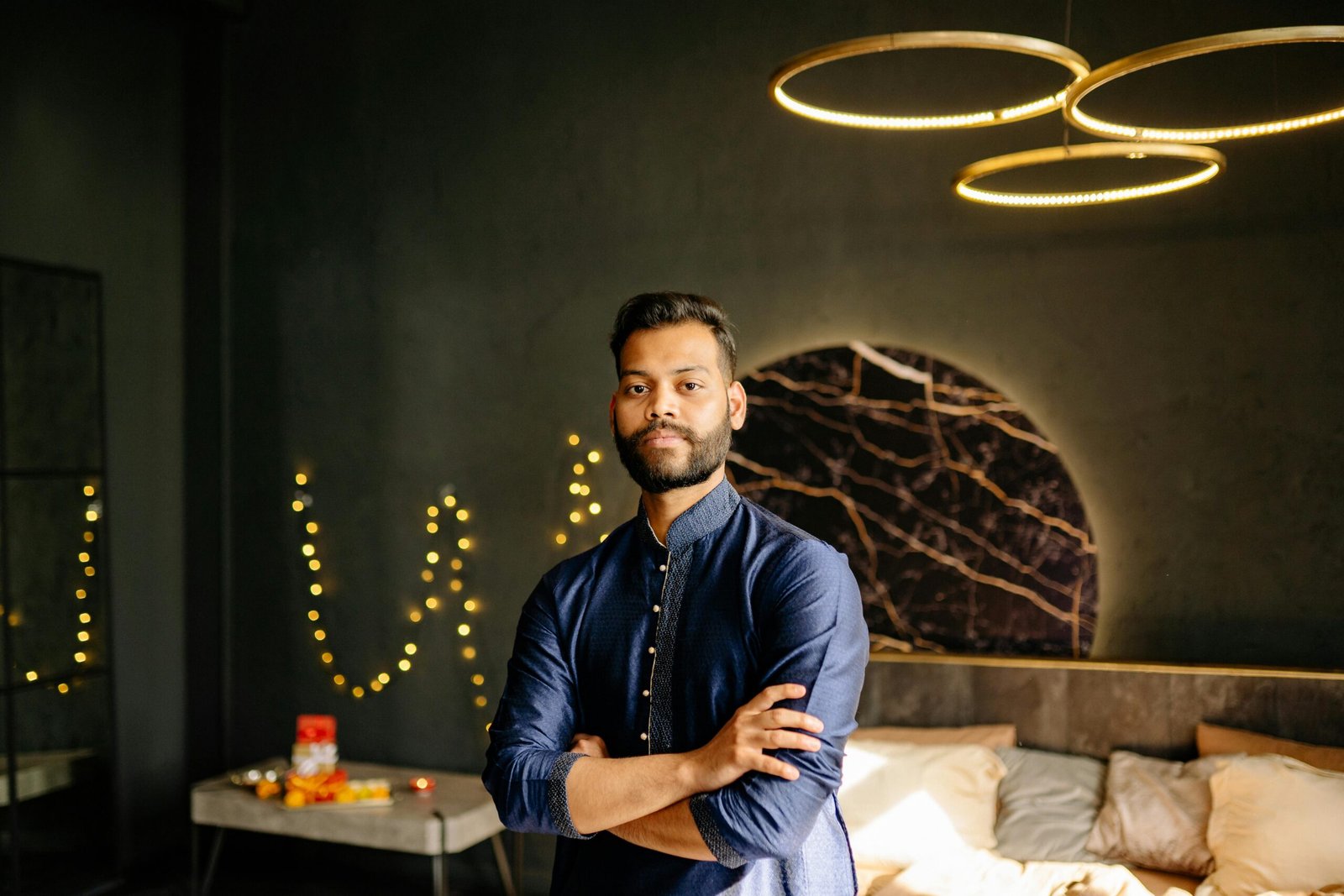 Portrait of a confident man in blue attire during Diwali celebration indoors with festive lights.
